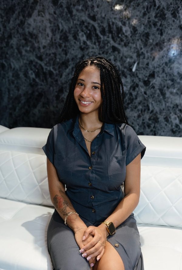 Lena Claire seated with hands folded, smiling warmly